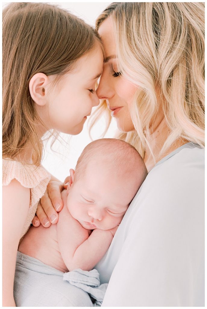 Mother nose to nose with little girl, holding newborn. Studio Session with Halleigh Hill
