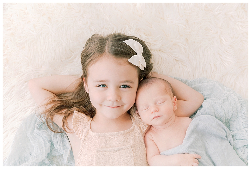 Little girl holding her brand new baby brother by Halleigh Hill