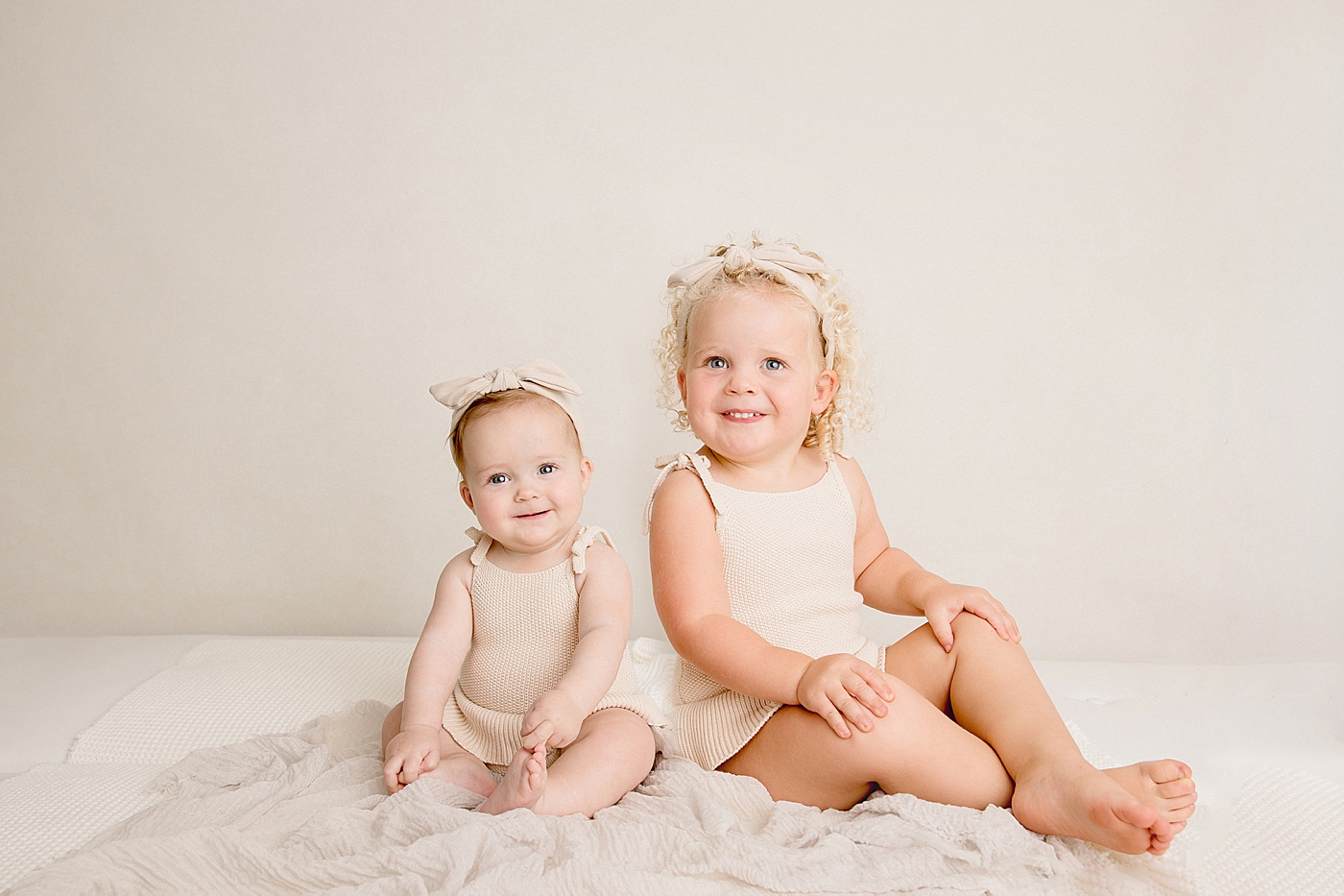 Toddler sisters in white sitting in the studio | Image by Halleigh Hill