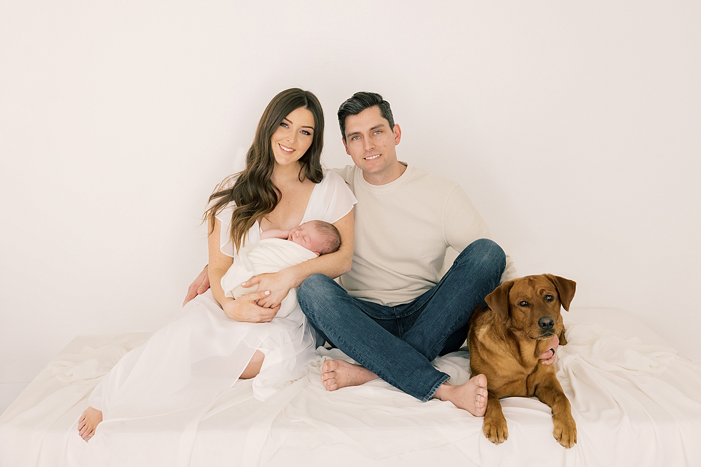 Mom and dad with their dog and new baby in the studio | Image by Halleigh Hill