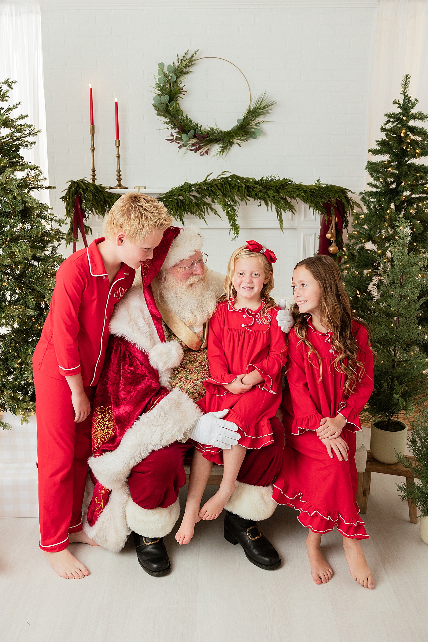 Three kids in red pajamas sitting with Santa | Image by Halleigh Hill