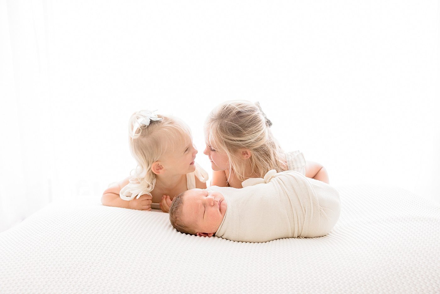 Big sisters snuggling with their new baby brother | Image by Halleigh Hill